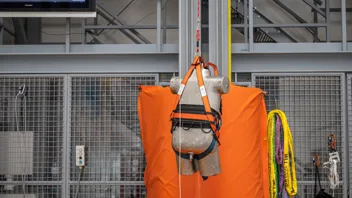 Ein Dummy hängt an einem Seil in einem Gurtsystem, das gerade einer genormten Prüfung unterzogen wird.
