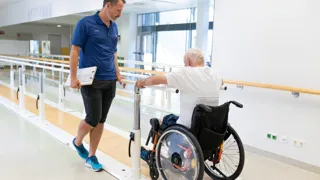 Älterer Mann im Rollstuhl und Therapeut beim Armtraining