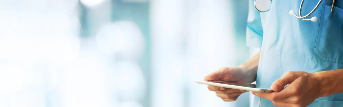 Ein anonym dargestellter Mediziner, der ein Tablet in den Händen hält Ein anonym dargestellter Mediziner, der ein Tablet in den Händen hält