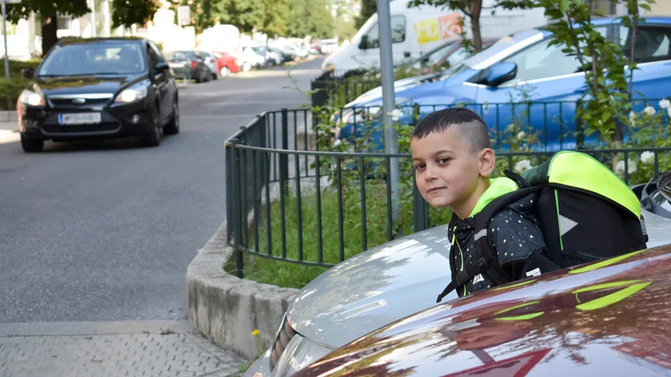 Schulweg Kind Parkende Autos 1440 Credit Jacquelinegodany Bub mit Schultasche schaut zwischen parkenden Autos auf die Straße