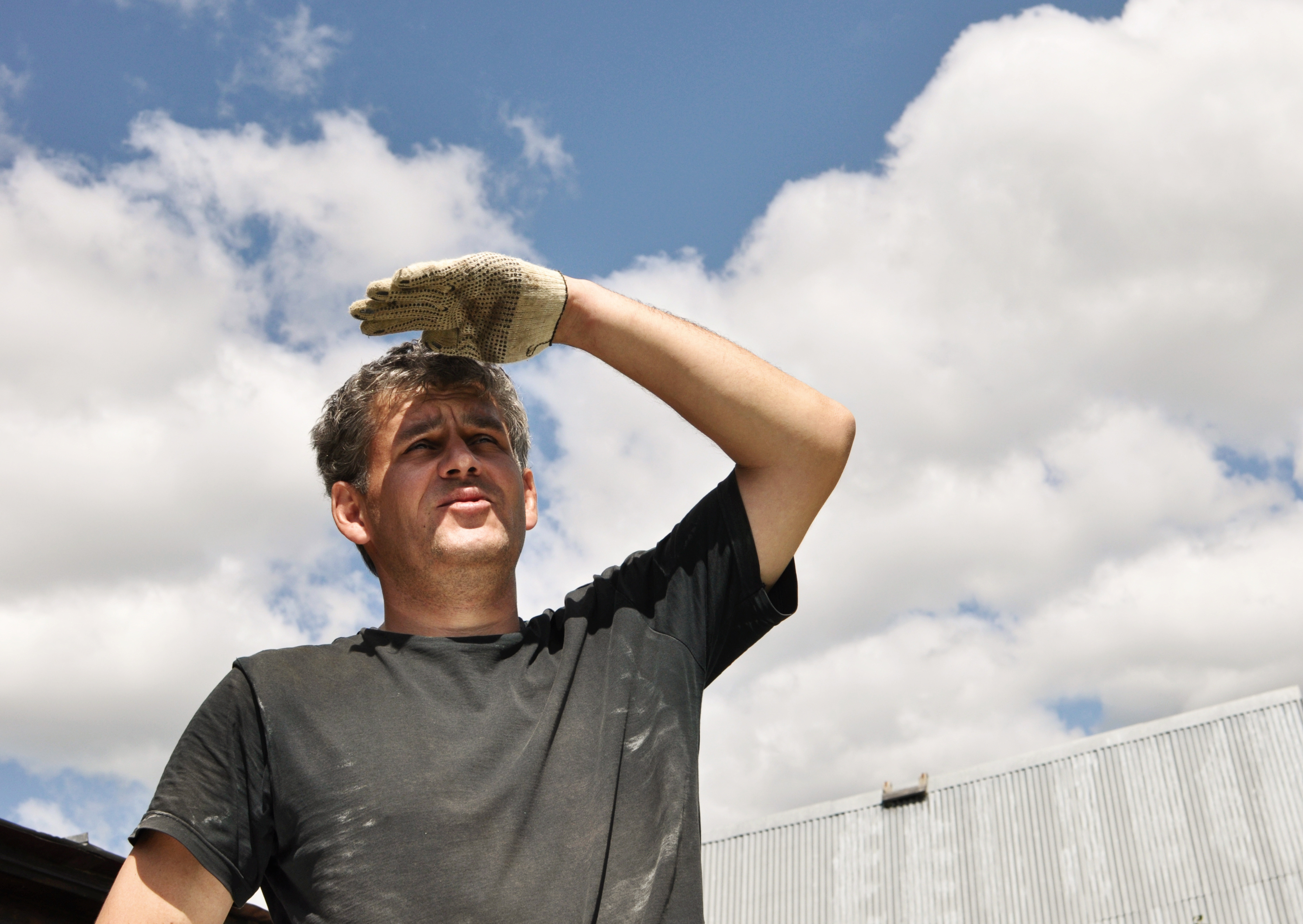 Ein Mann schützt mit der Hand sein Gesicht vor der Sonne