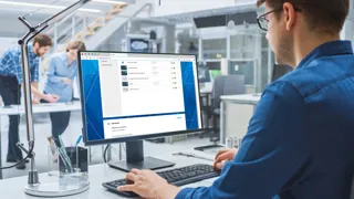 E-Learning Mann sitzt am Bildschirmarbeitsplatz und sieht die Kursübersicht im E-Learning Portal.
