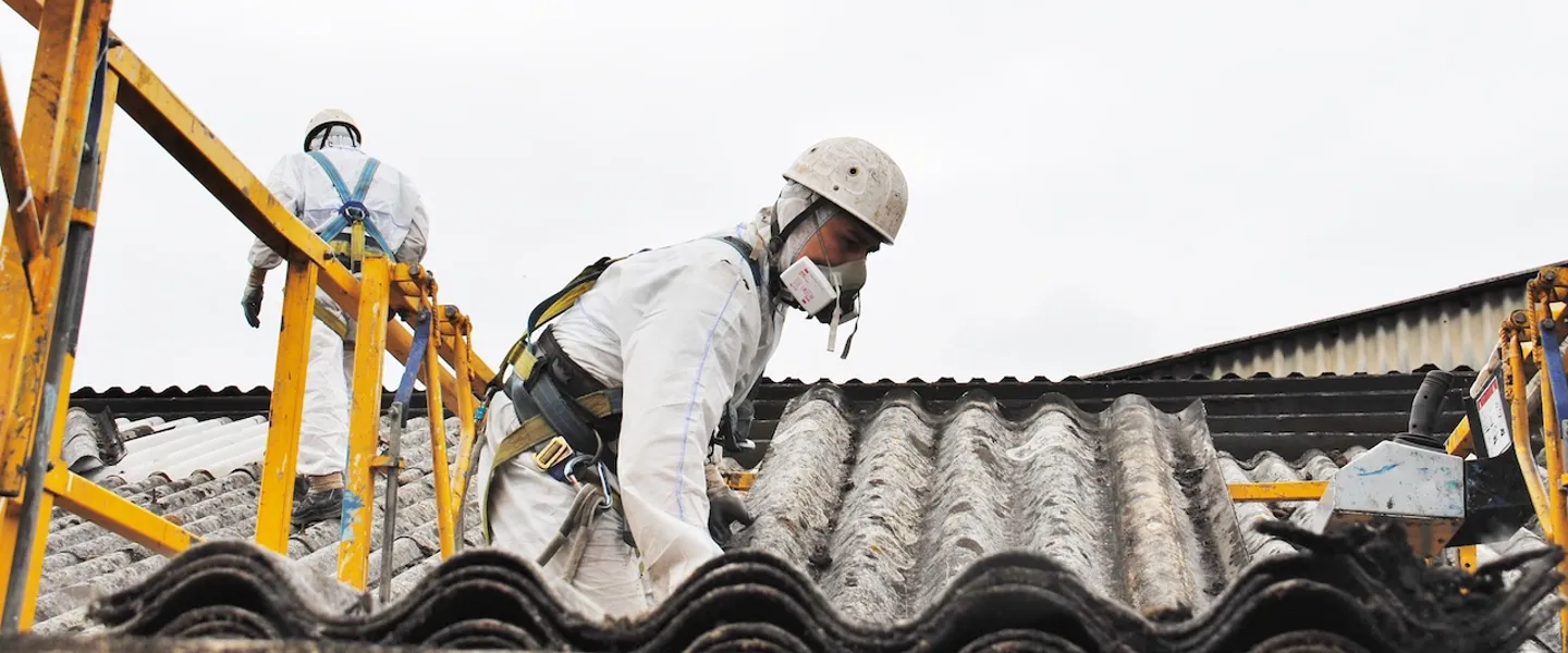 Arbeiter in Schutzausrüstung entfernen Asbest-Dach