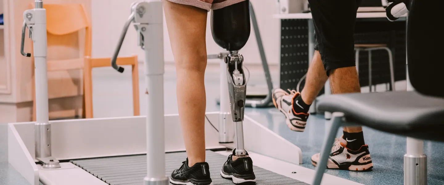 Eine Patientin mit Beinprothese bei einer Gangschulungsübung auf einem Laufband