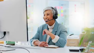 Adobestock 650170201 ©Wesley Jvr Peopleimages.Com WEB Eine mittelalte Frau mit Headset schaut auf einen Computer-Bildschirm