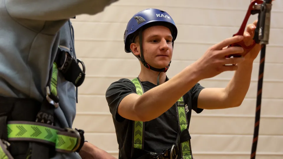 Junger Mann mit Helm, Kletterseil und Karabiner