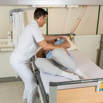 M105 Von Der Rueckenlage Zum Querbett Sitz Pflegefachkraft hilft Patient von der Rückenlage zum Querbett-Sitz zu gelangen
