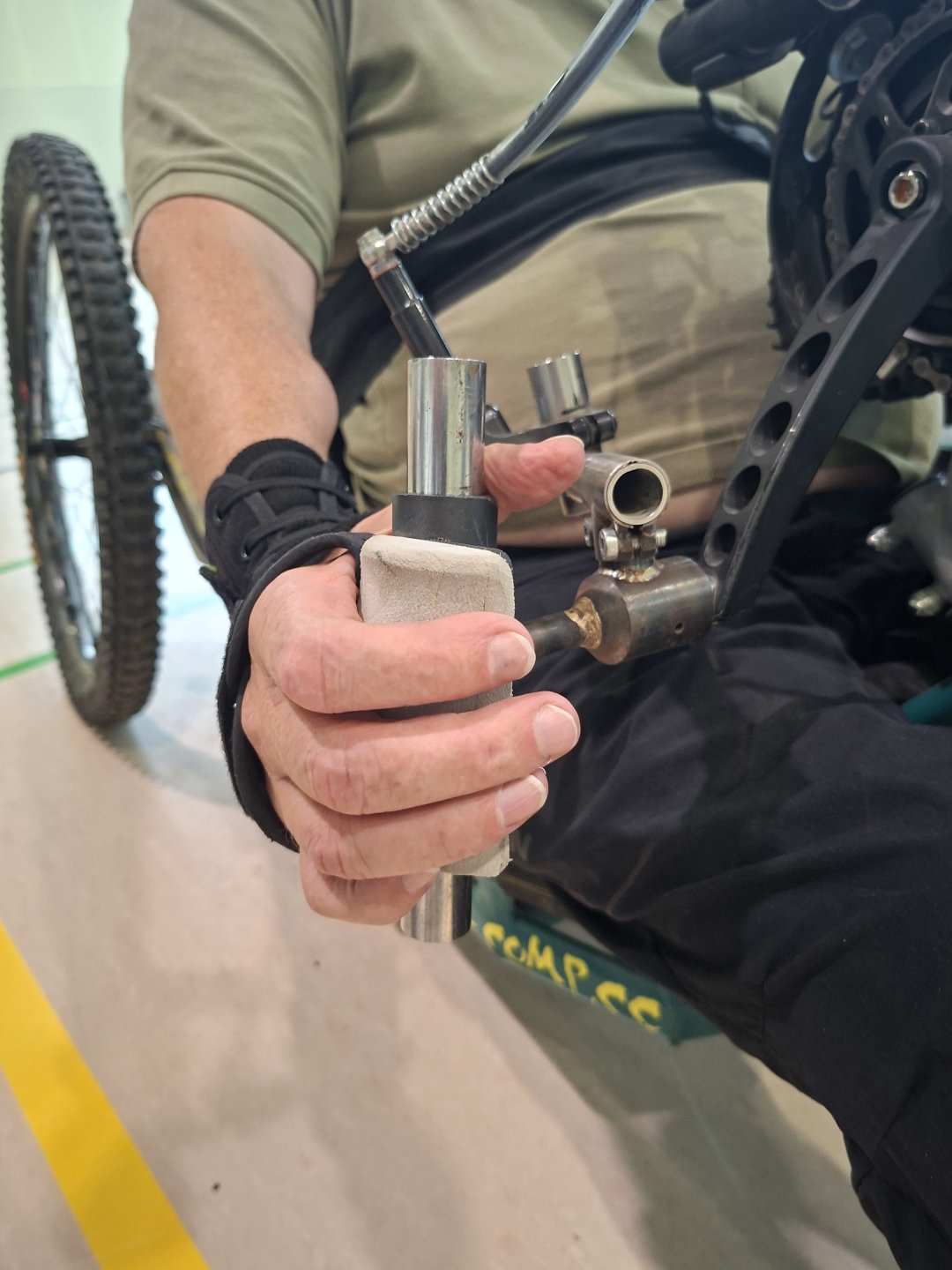 Person im Rollstuhl nutzt die spezielle Handsteuerung eines für Menschen mit Querschnittlähmung umgebauten E-Bikes im Parasportzentrum Häring.