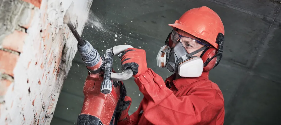 4.1.2.10_Lärm_AdobeStock_236846144.jpeg Arbeiter mit Gehörschutz beim Stemmen.