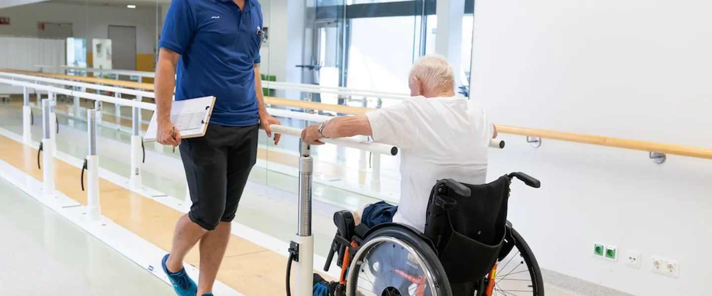 Älterer Mann im Rollstuhl und Therapeut beim Armtraining