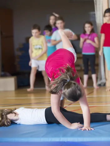 Schüler:innen auf einer Matte bei Fallübungen
