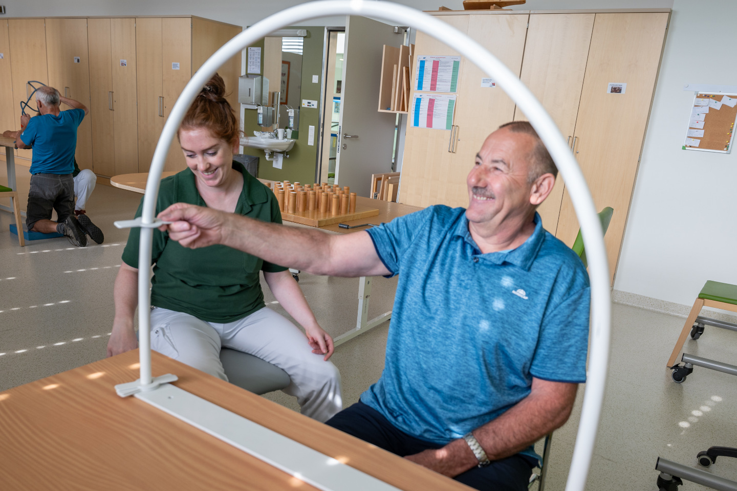 Eine Ergotherapeutin unterstützt einen Patienten bei einer ergotherapeutischen Geschicklichkeitsübung
