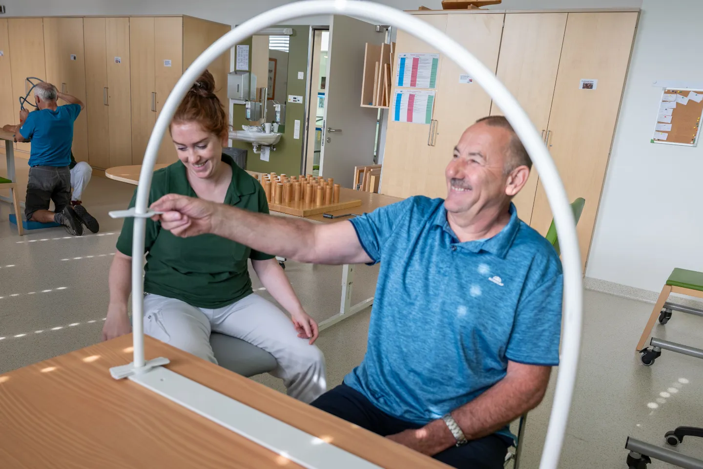 Eine Ergotherapeutin unterstützt einen Patienten bei einer ergotherapeutischen Geschicklichkeitsübung
