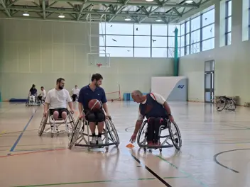 Drei Rollstuhlbasketballspieler im Spiel, im Hintergrund sind drei weitere Spieler:innen