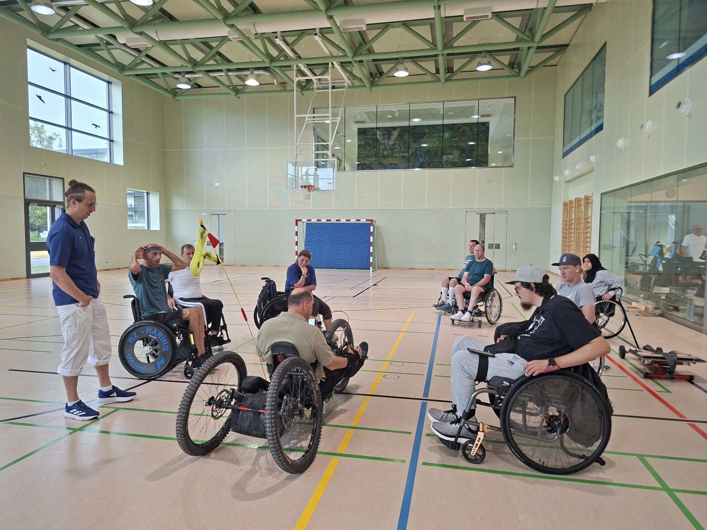 Vorstellung eines für Menschen mit Querschnittlähmung angepassten E-Bikes vor Patientinnen und Patienten in der Sporthalle des Parasportzentrums Häring.
