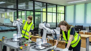 Adobestock 1599958487 Web Credit Adobestock Vstudio Zwei Frauen in Warnwesten hantieren mit Robotern, die auf einem Tisch stehen.