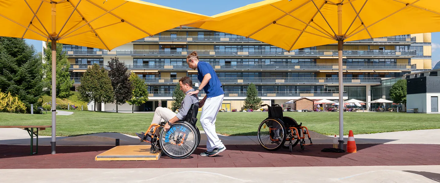 Patient bei Rollstuhltraining mit Therapeut in den Parkanlagen des AUVA-RZ Häring Patient bei Rollstuhltraining mit Therapeut in den Parkanlagen des AUVA-RZ Häring