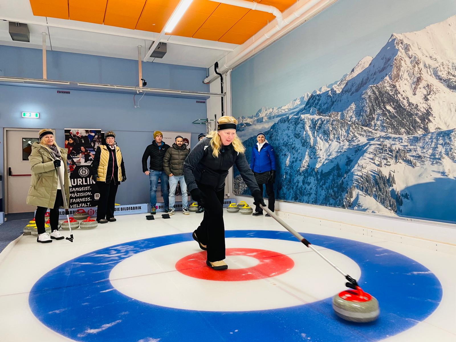 Eine Teilnehmerin in Aktion am Eis, im Hintergrund sind einige weitere Personen erkennbar. 