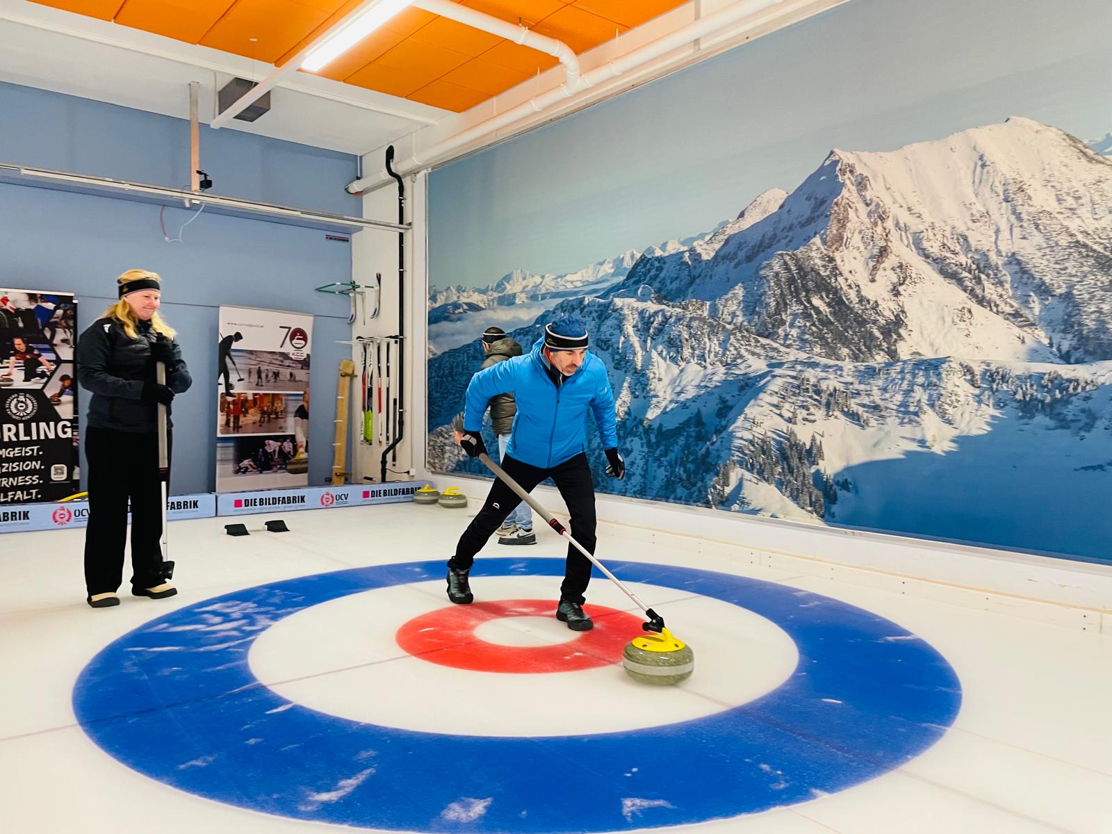 Ein Teilnehmer in Aktion am Eis, im Hintergrund zwei weitere Personen.