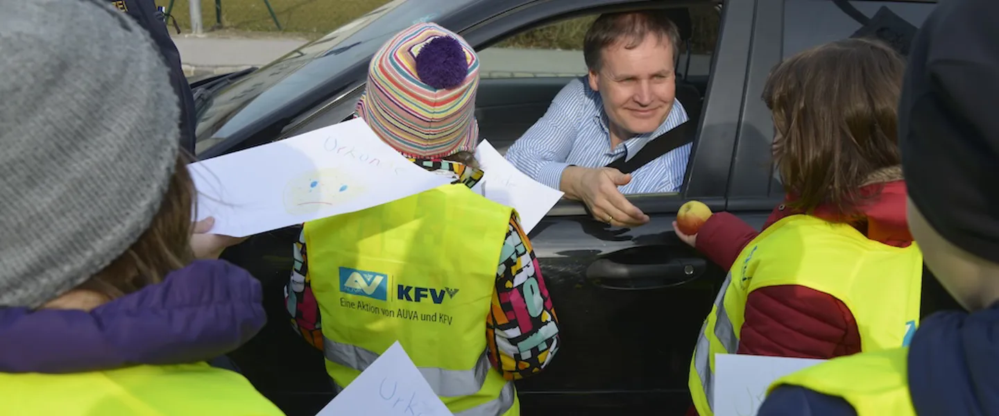 Mann im Auto umringt von Kindern, die an der Aktion teilnehmen