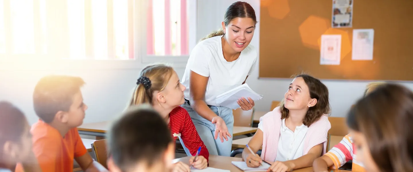 Gruppe Schüler:innen an einem runden Tisch Eine Gruppe Schüler:innen an einem runden Tisch erhält von der Lehrperson gerade eine Erklärung