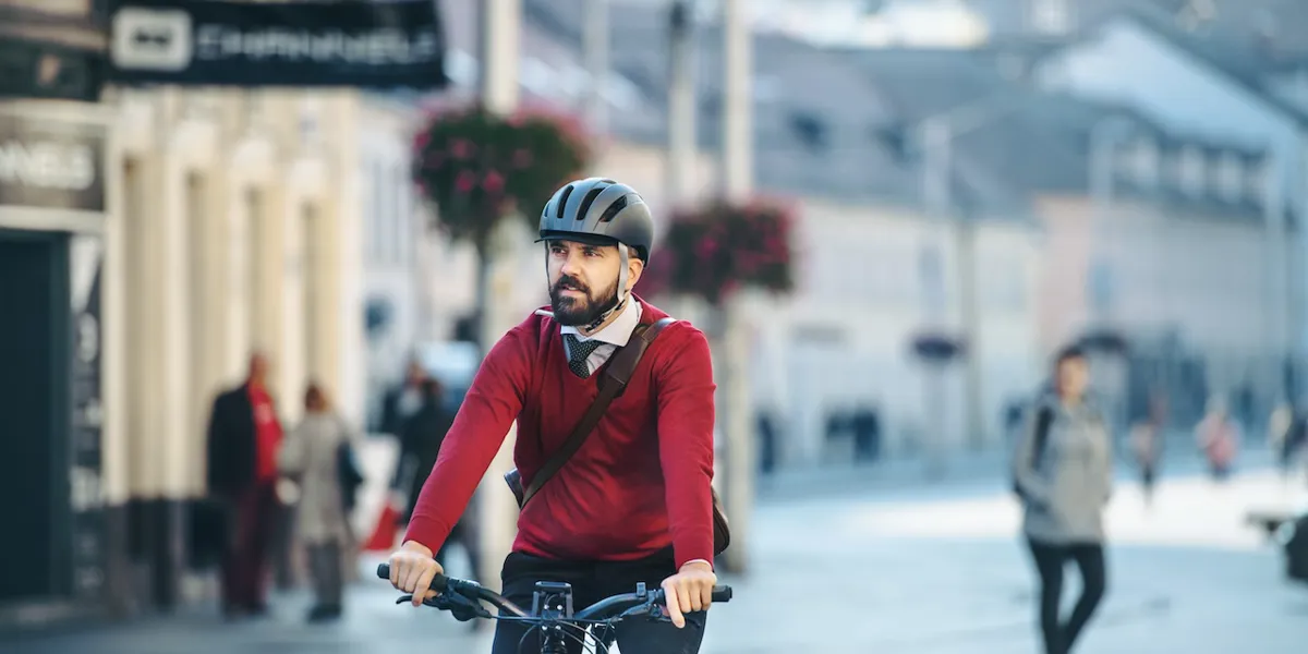 Ein im Business Outfit gekleideter Radfahrer fährt in städtischer Umgebung