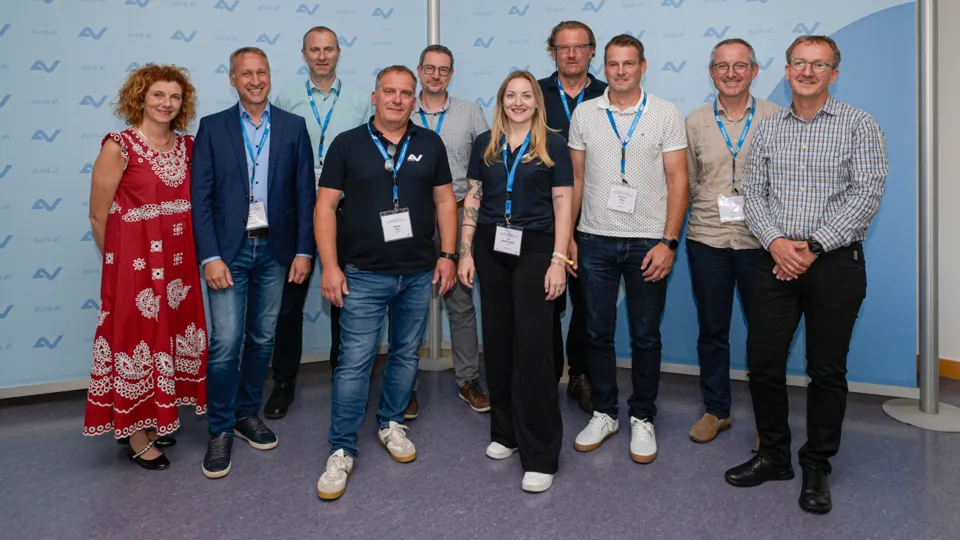 Eine Gruppe von Erwachsenen steht vor einer AUVA-Logowand