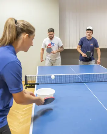 Eine Spielerin auf der einen und zwei Spieler auf der anderen Seite im Tischtennis-Match