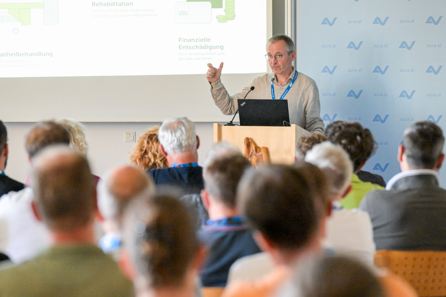 Ein Mann steht hinter einem Rednerpult und hält einen Vortrag vor einem Publikum