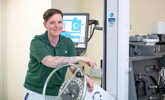 Eine Mitarbeiterin des RK Tobelbad steht vor einem Gerät, das der Arbeitssimulation im Rahmen Wiedereingliederung ins Berufsleben dient. Eine Mitarbeiterin des RK Tobelbad steht vor einem Gerät, das der Arbeitssimulation im Rahmen Wiedereingliederung ins Berufsleben dient.