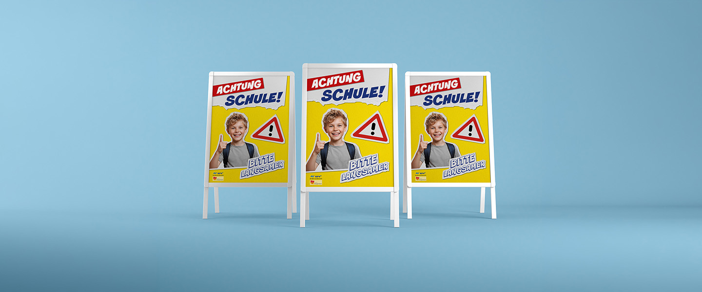 Fotomontage von drei Plakatständern, die einen Schuljungen mit erhobenem Zeigefinger, ein Achtung-Zeichen und den Schriftzug "Achtung Schule! Bitte langsamer" zeigen.
