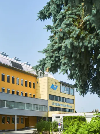 Außenansicht UKH Klagenfurt am Wörthersee, teils mit herabhängenden Zweigen eines Nadelbaums. Außenansicht UKH Klagenfurt am Wörthersee, teils mit herabhängenden Zweigen eines Nadelbaums.