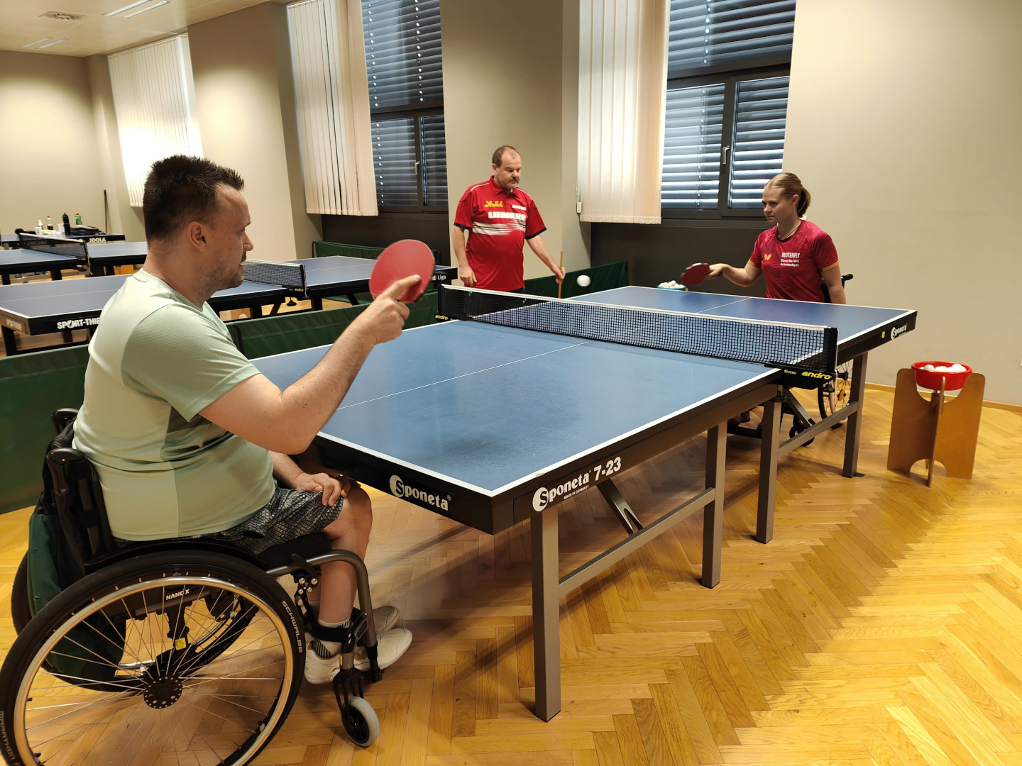 Rollstuhltischtennis: Im Bild sind eine Spielerin und zwei Spieler