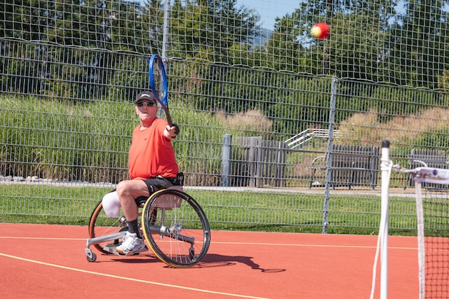 Ein Mann befindet sich beim Rollstuhltennis mitten im Schlag. 
