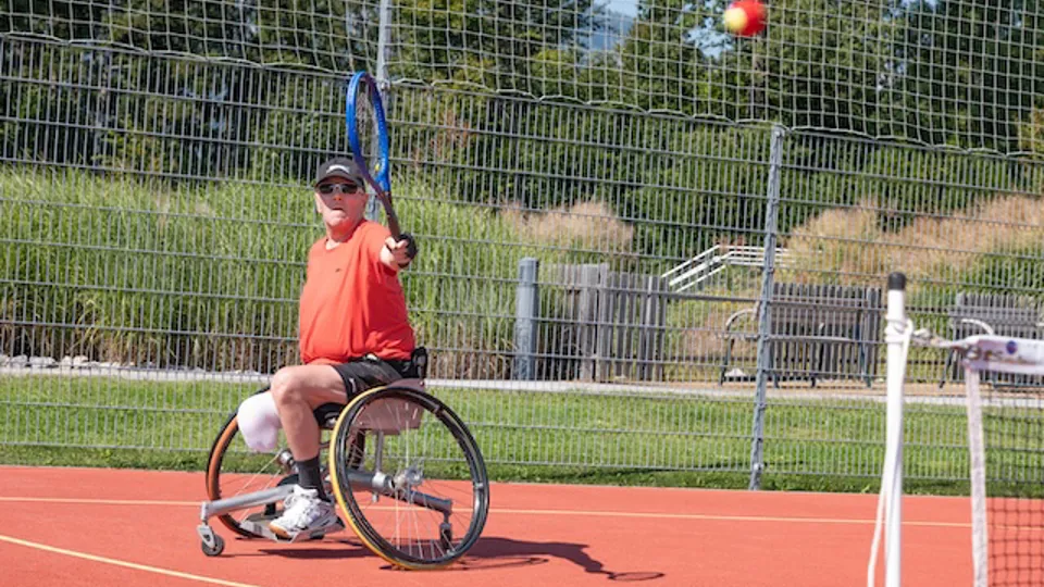 Ein Mann befindet sich beim Rollstuhltennis mitten im Schlag.