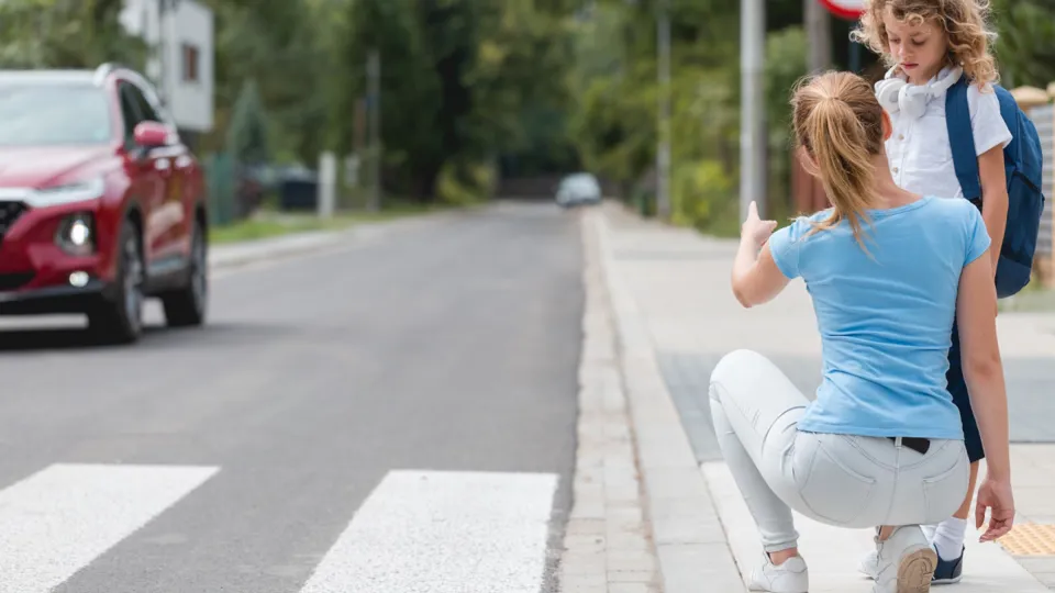 Adobestock 459451364 1440 (C)Photographee(Punkt)Eu Mutter kniet erklärend vor ihrer Tochter vor einem Zebrastreifen