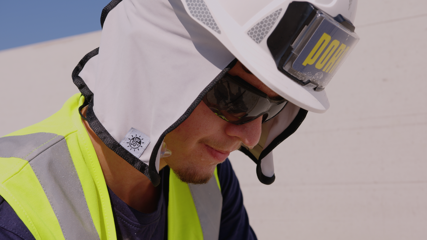 Nahaufnahme eines Bauarbeiters in Warnweste mit Schutzhelm und Nackenschutz