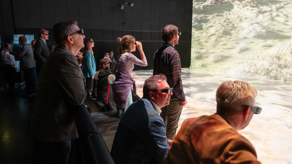 Personen mit VR-Brillen schauen auf eine Projektion