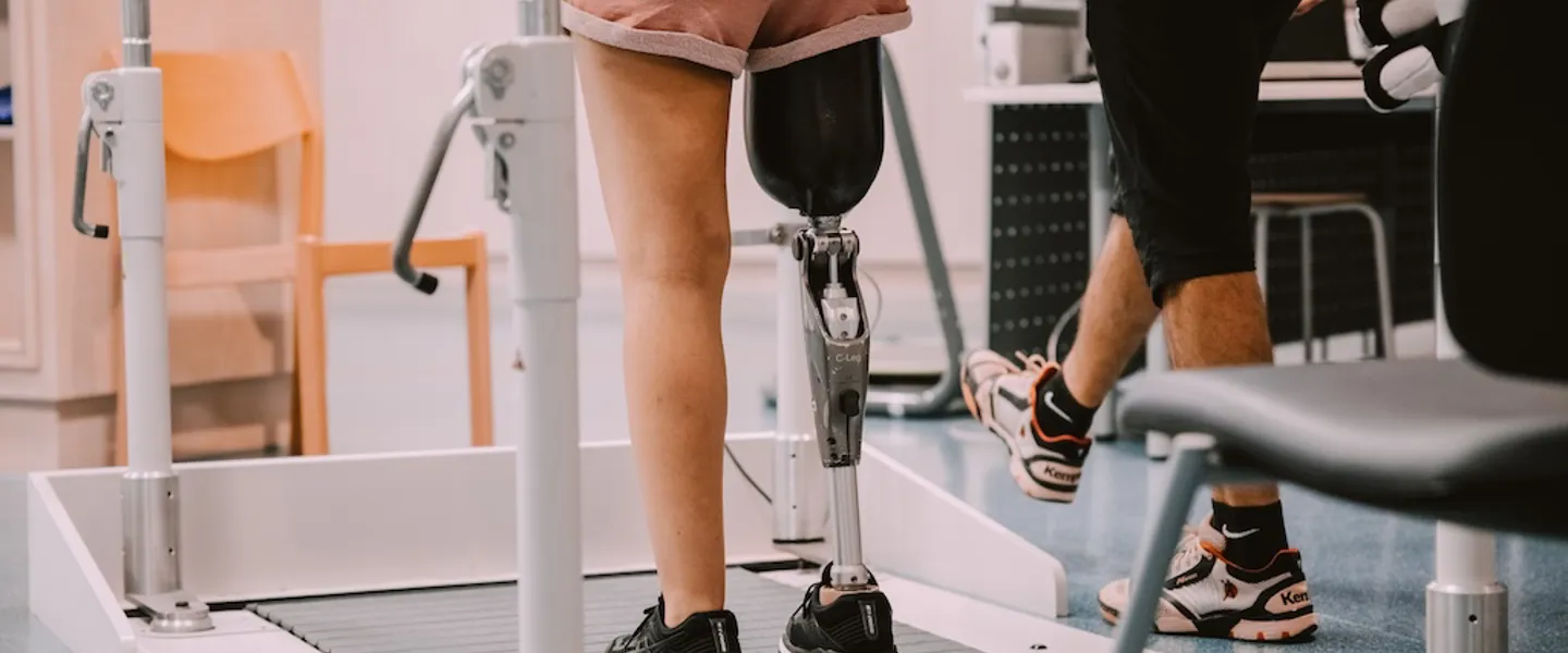 Eine Patientin mit Beinprothese bei einer Gangschulungsübung auf einem Laufband