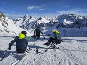 Drei Monoskifahrer:innen bei der Abfahrt