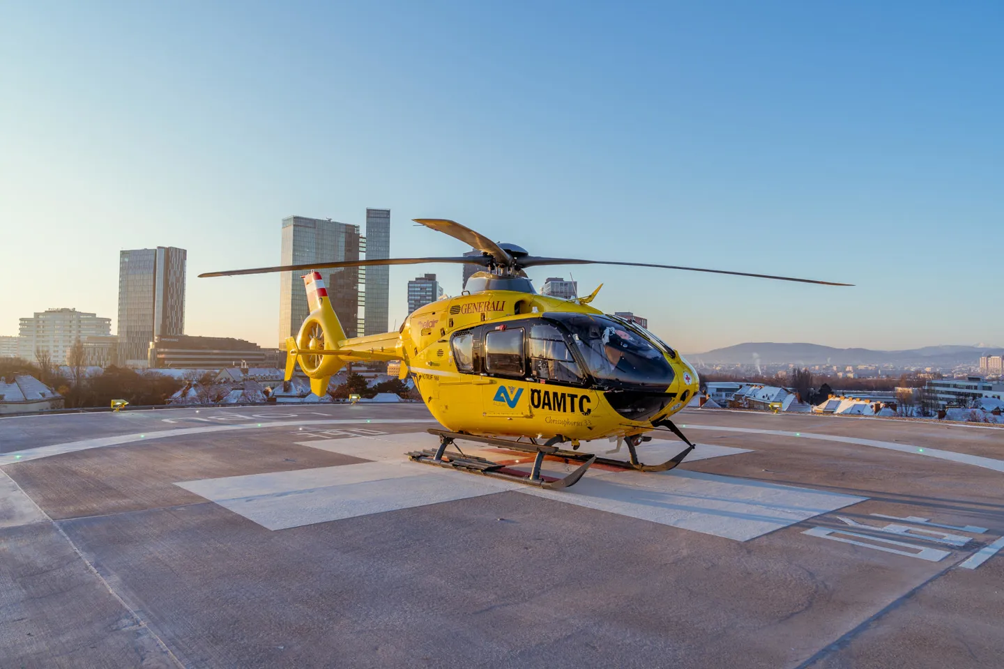 Gelber Rettungshubschrauber steht auf dem Landeplatz des Traumazentrums Wien Meidling