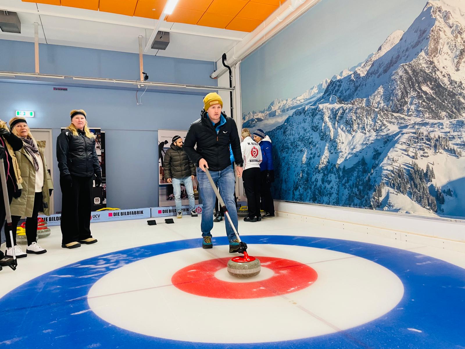 Ein Teilnehmer in Aktion am Eis, im Hintergrund weitere Personen erkennbar. 