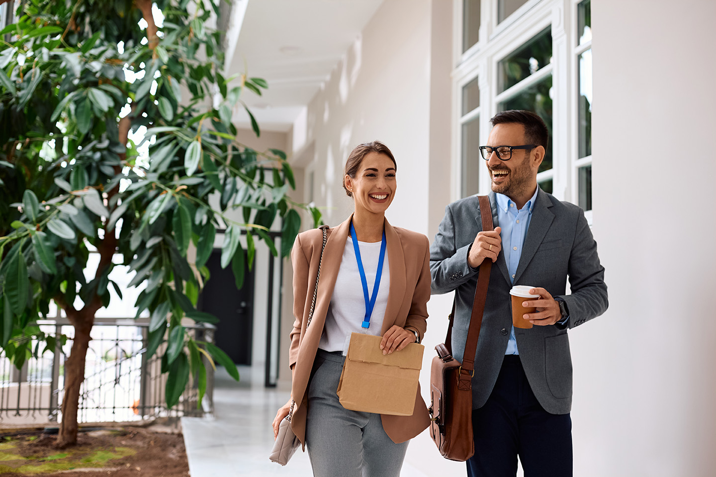 Ein junger Mann und eine junge Frau in Business-Outfits gehen nebeneinander vor einem Gebäude
