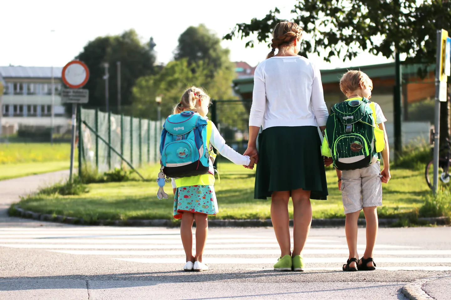 PA 2024-08-26 Training für sicheren Schulweg - Zebrastreifen (2) Zwei Schulkinder mit gelber Warnweste der AUVA beim Sicherheitstraining vor Überquerung eines Zebrastreifens mit dritter Person