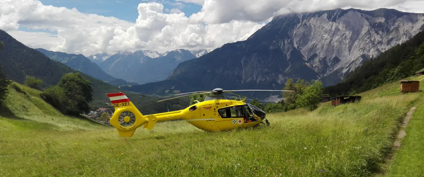 Ein gelber Rettungshubschrauber ist auf einer grünen Wiese in den Bergen gelandet.   Ein gelber Rettungshubschrauber ist auf einer grünen Wiese in den Bergen gelandet.