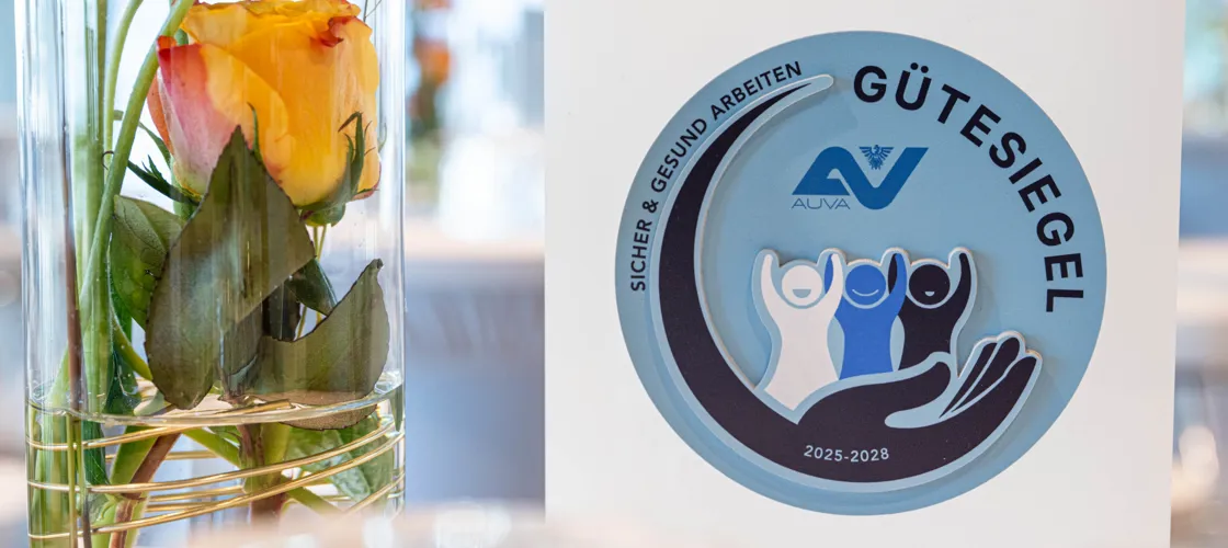 REI0234 H Credit Rreichhart Trophäe mit AUVA-Gütesiegel-Aufdruck neben einer Blumenvase