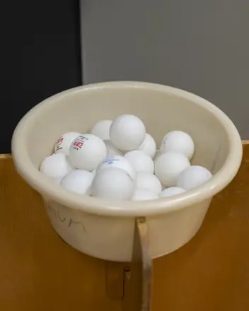 Viele Tischtennisbälle liegen in einem Topf