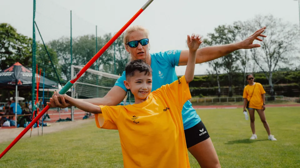 Paralympics-Athletin Natalija Eder unterstützt ein Kind beim Speerwurf