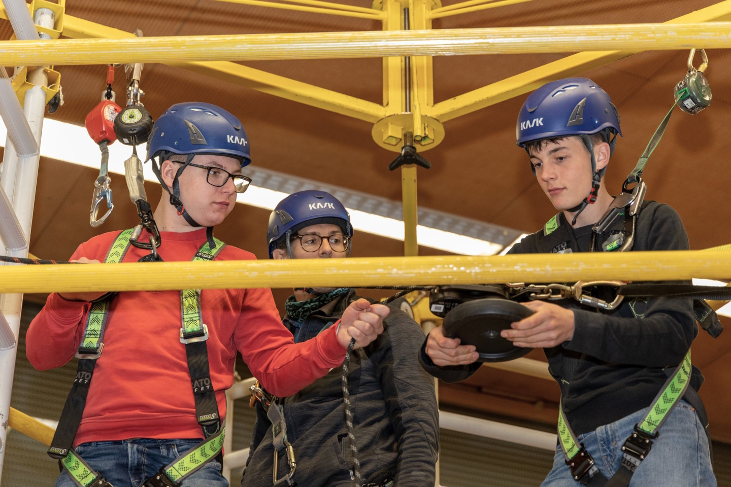 Drei junge Männer auf einem Kletterturm