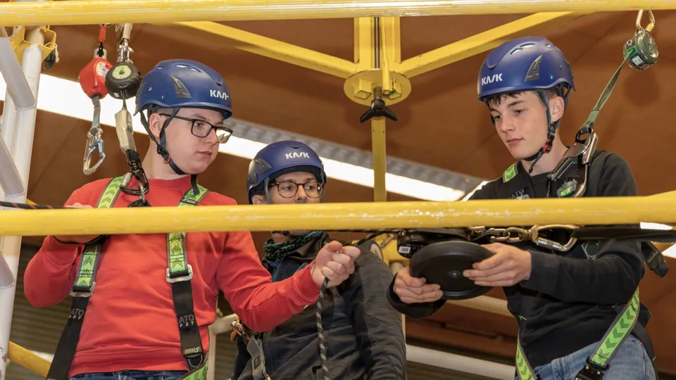 Drei junge Männer auf einem Kletterturm